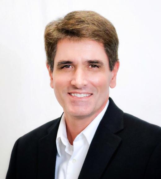 Michael smiles at the camera in a suit in front of a white background.